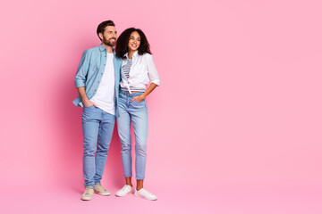 Young couple standing together in casual outfits against a solid pink background