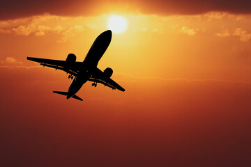 Obraz premium Airplane Silhouette at Sunset: A powerful silhouette of an airplane taking off against a fiery orange sunset, evoking feelings of adventure, freedom, and new beginnings.