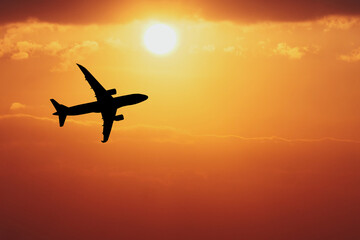 Sunset Flight Silhouette: A majestic airplane silhouette is captured against a vibrant, fiery sunset, symbolizing travel, adventure, and the freedom of flight.