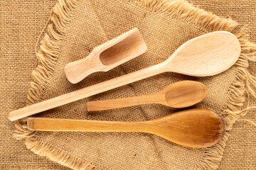 Wooden kitchen spoons on jute cloth, macro, top view.