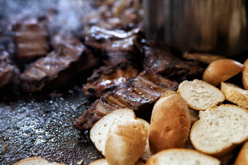 Close-up of many pieces of bread with meat on the grill in the background. Lots of bread on the grill with smoke in a pronounced texture. Street food festival.