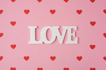 Red hearts pattern, love romantic concept, top view. Beautiful cute hearts on pastel pink background with white love in the middle. Valentines Day greeting card art. Flat lay composition.