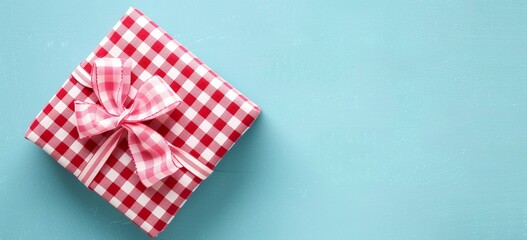 Obraz premium Red and white checkered Christmas gift box on light blue background