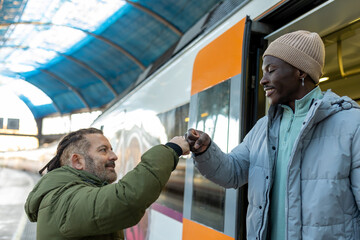 Two friends of different ethnicities saying goodbye at a train station