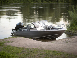 Sport boat out of aluminum at a slip place next to a river. Empty motor boat with an outboard engine in the nature in Germany.