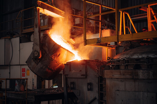 Molten metal pouring in an industrial foundry Intense heat and sparks illuminate the scene