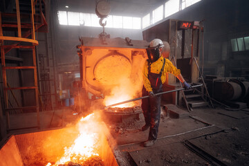 Metalworker stirring molten metal in a foundry