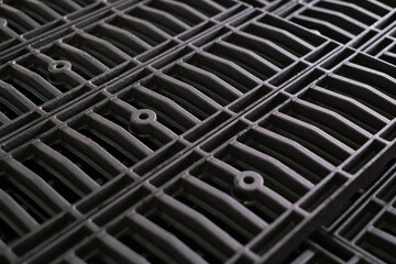 Close up view of a dark colored metal grating with a repeating pattern