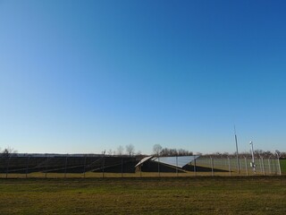 side view of a large solar panel complex in a field on a clear day, industrial production of solar energy for conversion to electricity, protected area with photovoltaic panels
