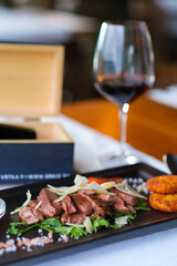 Seared steak slices atop greens with parmesan and crispy sides
