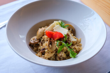 Mushroom risotto garnished with parmesan cheese and cherry tomatoes