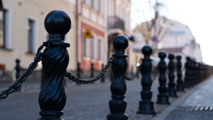 Iron posts with chains, fences by the road. An old, vintage fence