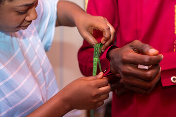 Female Tailor is measuring her client with measuring tape