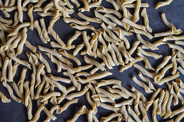 Pasta is scattered on a black surface and photographed close-up. A composition of tubular pasta that is scattered on the table.