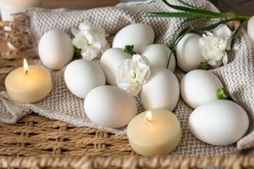 Decorative white eggs arranged with flowers and candles for Easter celebration in springtime
