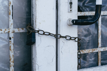 The chained door of the store. A locked white door. A chain with a lock
