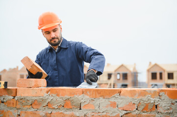 Installing brick wall. Construction worker in uniform and safety equipment have job on building