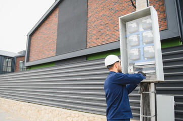 A male electrician works in a switchboard