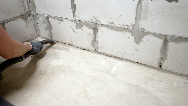 Construction worker cleaning concrete dust with industrial vacuum cleaner