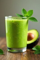 Fresh green avocado smoothie in a glass on a natural wood surface, healthy, nutrition