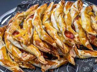 baked ham and cheese rolls, finger food appetizers on black napkin in silver tray, close up