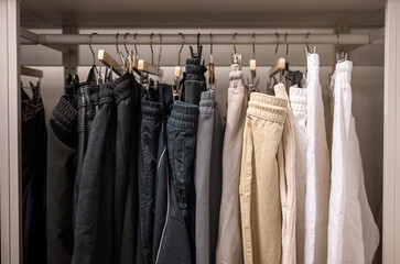 Variety of pants in different colors organized on a rack in thrift store