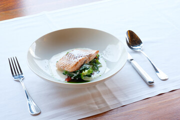 Pan seared fish fillet served with a creamy sauce and sauteed greens