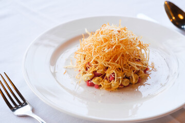 A savory dish featuring crispy fried strands atop a creamy base