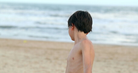 Young boy turning body towards beach