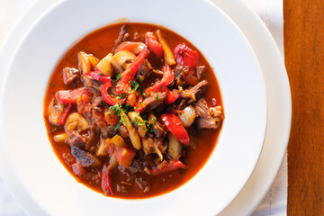 Hearty stew with meat peppers and mushrooms in a rich tomato sauce