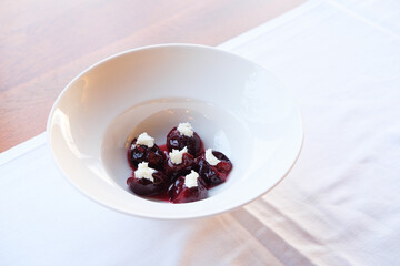 Plated dessert featuring poached fruit and a dollop of cream