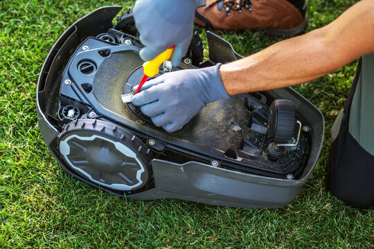 Repairing a Robotic Lawn Mower on Grassy Turf in the Afternoon