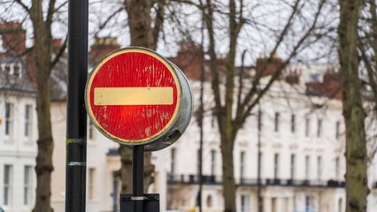 A worn no-entry sign in a regency town setting
