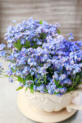 Bouquet of forget-me-not flowers in ceramic vase.