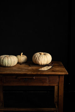 Rustic table with pumpkins and knife against dark background
