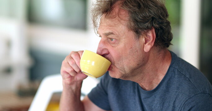 Older retired man taking a sip of coffee or tea