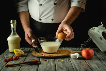 Hands skillfully prepare a mixture in a glass bowl, combining egg, milk, and lemon. Fresh apples and a wooden board enhance the inviting atmosphere of this culinary creation