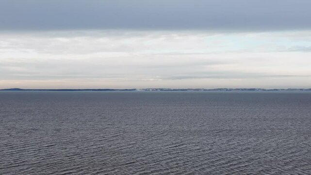 A panoramic view of the vast Curonian Lagoon, with a barely visible sandbank, captured at sunset during wintertime. Europe Lithuania.