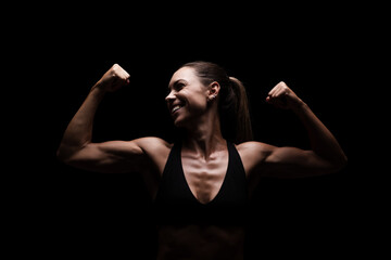 Confident Female Athlete Displaying Strength and Fitness in Dark Studio Setting