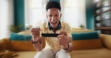 Excited man, portrait or winning race with phone for esport competition or mobile gaming on sofa at home. Happy, male person or gamer with victory or rank for speed simulation or virtual championship © peopleimages.com