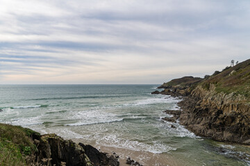 L'écume blanche danse sur les vagues aux teintes émeraude sur la plage du Minou, avec un ciel d'hiver voilé et le sable clair créant un contraste apaisant.