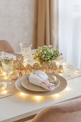 Festive Easter table setting with Easter bunny made from napkin decorated lights. Easter celebration concept