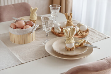 Festive Easter table setting with Easter bunny made from egg and knitted ears. Easter celebration concept