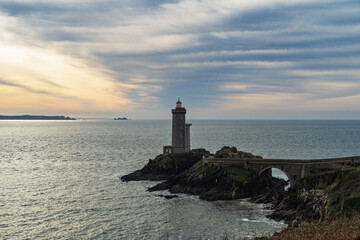 Le phare du Petit Minou &agrave; Plouzan&eacute; sous un ciel d&rsquo;hiver voil&eacute;, m&ecirc;lant nuances de bleu, blanc, gris et jaune. La mer d'Iroise refl&egrave;te cette lumi&egrave;re douce et hivernale.