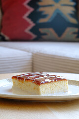 A slice of delicious custard cake drizzled with caramel sits on a plate