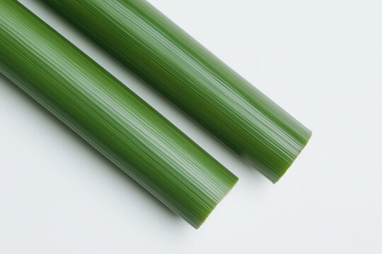 Green Plastic Rods: Two sleek, vibrant green plastic rods lie parallel, showcasing their smooth texture and consistent color.  The image is simple, clean.