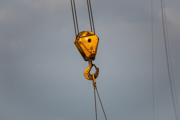 Fototapeta premium A yellow crane hook is suspended in the air