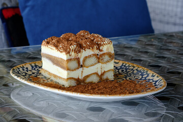 A delectable slice of tiramisu layered with creamy filling and coffee soaked ladyfingers dusted with cocoa