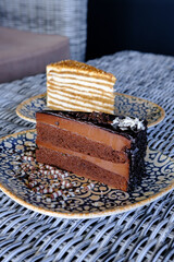 Two slices of cake one layered and light the other rich chocolate sit on patterned plates