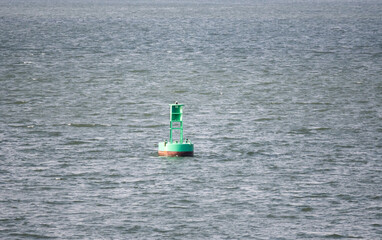 A green buoy sits in the middle of the ocean